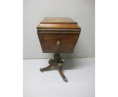 A REGENCY MAHOGANY TEAPOY the rectangular hinged lid above a panelled frieze on turned column and tripod base with brass caps