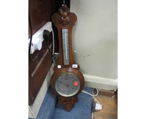 AN EDWARDIAN OAK BANJO BAROMETER AND THEMOMETER with foliate carved case containing silvered dials 90cm high