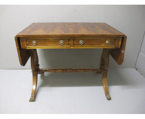 A GEORGIAN STYLE YEW WOOD SOFA TABLE the rectangular hinged top above two frieze drawers on lyre end supports with splayed le