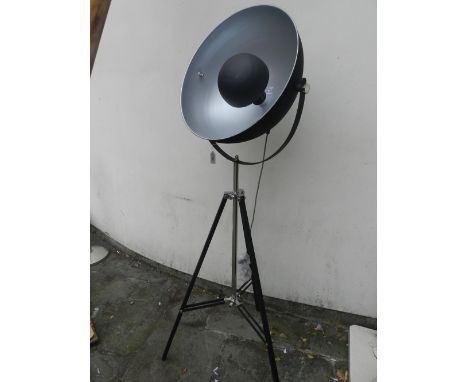 A Contemporary standard lamp in the form of a spotlight, raised on ebonised tripod legs.