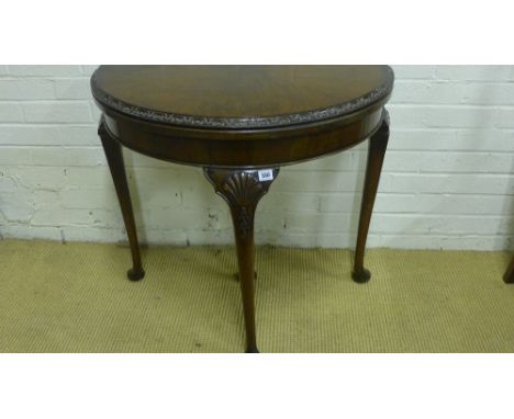 An early 20th century walnut demi lune card table with carved moulded edge and shell carving to legs 