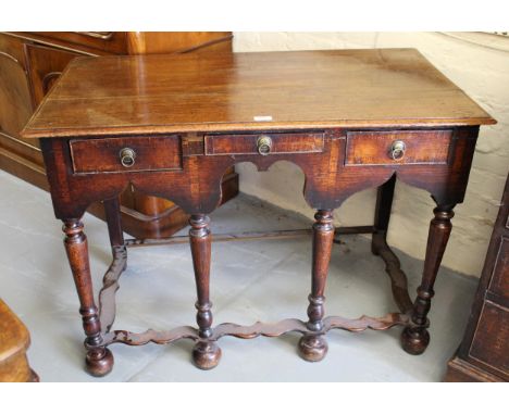 18th Century oak side table, having an arrangement of three short drawers with brass ring handles on baluster turned supports