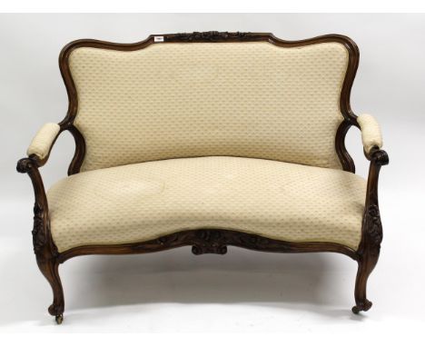 19th Century floral carved rosewood and beige upholstered two seat sofa, having cabriole front supports with brass casters, 1