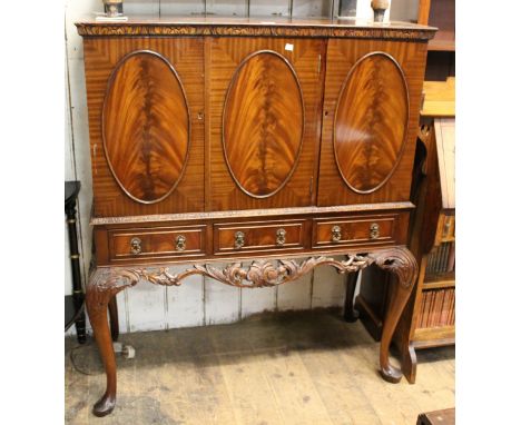 Modern mahogany drinks cabinet, having three flush panelled doors above three short drawers on carved cabriole supports, 109c