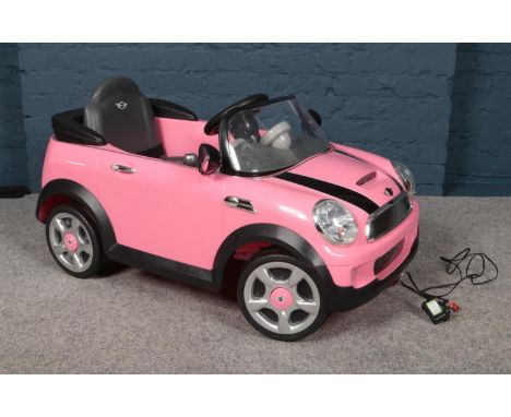 A child's electric pink Mini Cooper S car together with charging plug.  Please note this item has not been tested.