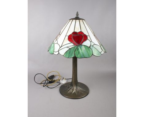 A Tiffany style table lamp, the domed glass shade with opaque panels and flower heads on a tree cast stem and spreading base.