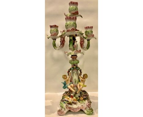 A Sitzendorf porcelain four light two section candelabrum, the column with seated putto, encrusted with flowers throughout, 3