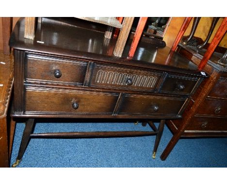 AN ERCOL DRESSING CHEST, of three short over two long drawers with tapered spindle legs terminating in brass caps and castors