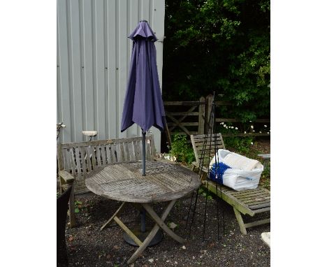 A ROUND TEAK GARDEN TABLE, with parasol, a teak garden bench, a metal vine frame and a teak garden lounger (5)