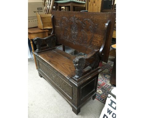 An oak monks bench with carved top and lift up seat