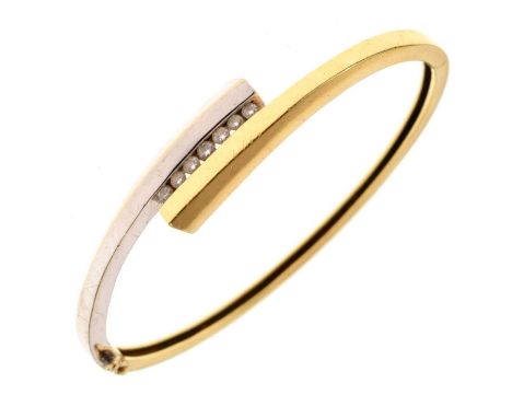 Two-colour diamond set hinged 18ct gold bangle, Birmingham 2002, of crossover design enclosing a line of seven brilliant cuts