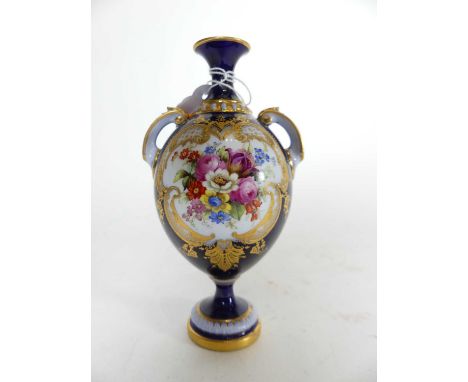 A Royal Worcester porcelain vase, of twin handled ovoid form, handpainted with flowers within a gilt cartouche, on a blue gro