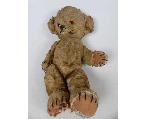 An early 20th century Merrythought bear, blond mohair with articulated limbs and glass eyes, stitched label to left foot, hei