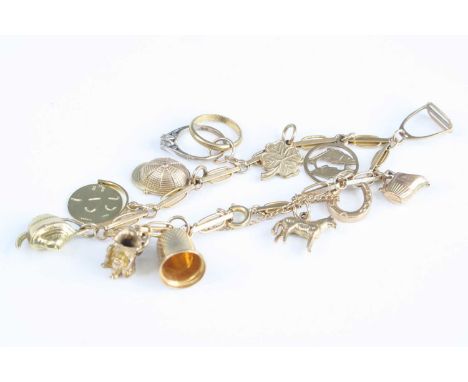 A 9ct gold bracelet containing assorted principally 9ct gold charms to include teapot, toby jug, thimble, horseshoe, etc, gro