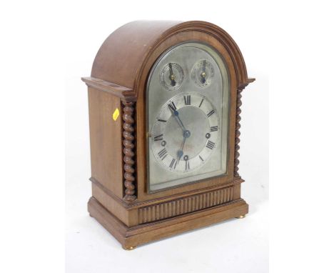 An early 20th century mahogany cased mantel clock, the silvered arched dial having applied chapter ring with Roman numeral ma