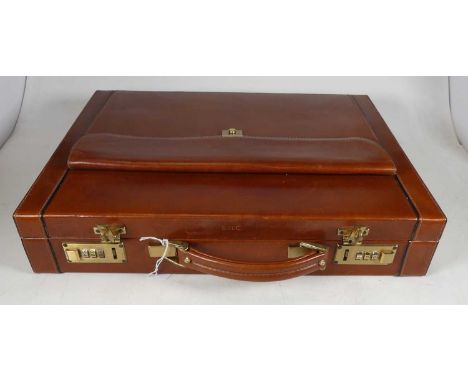 A mid 20th century gentleman's tan leather briefcase having twin combination locks, the exterior embossed BHC in gilt, openin