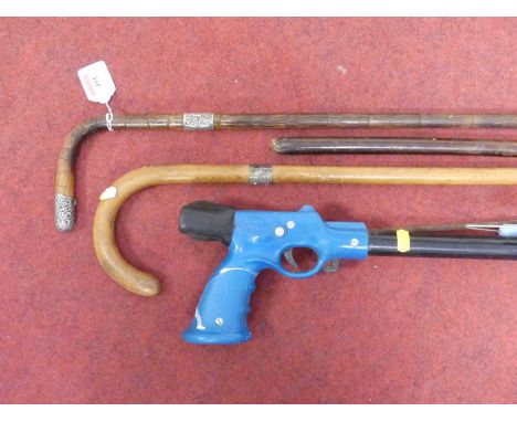 A Victorian silver mounted stained bamboo walking cane, length 93cm, together with another, and a harpoon gun