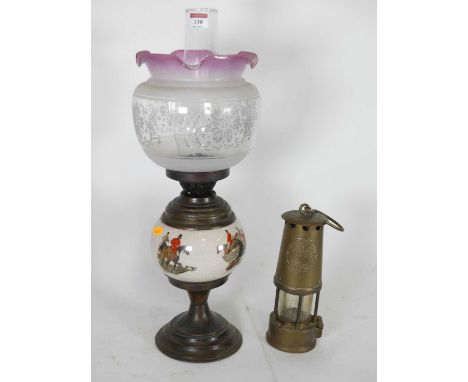 An early 20th century oil lamp, having an acid etched glass shade and a pottery body, transfer decorated with a hunting scene