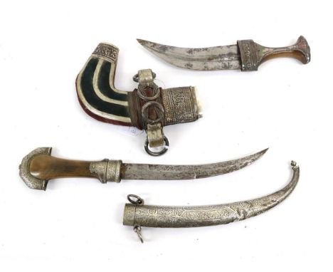 An Early 20th Century Moroccan Jambiya, with 21cm double edge curved steel blade, rhinoceros horn grip with foliate chased lo