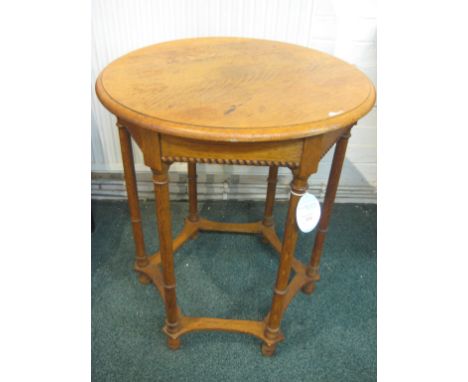 A Waring and Gillow light oak circular side table, on six columnar legs stretchered at the feet, applied manufacturer's label