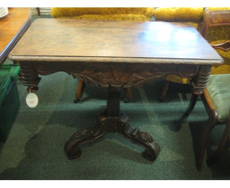 Dark oak rectangular side table with a broad apron carved with foliage in a rustic style, standing on a scrolled column and s