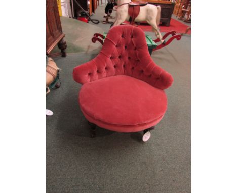 A Victorian nursing chair in pink button back upholstery with triangular shaped backrest, on turned legs with beaded metal tr
