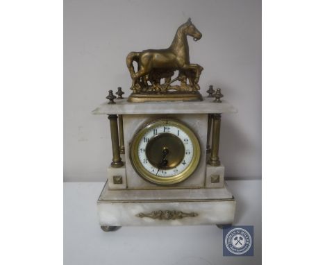 A brass and alabaster mantel clock with enamelled dial surmounted by a horse, with pendulum and key 