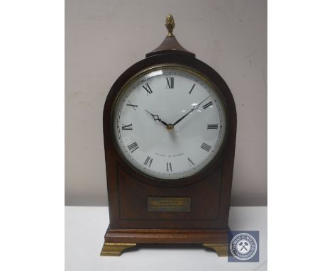 A 20th century inlaid mahogany mantel clock with lion mask handles by Comitti of London on brass feet 