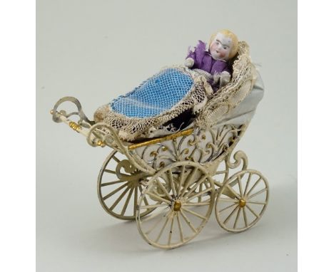 Miniature painted soft metal pram and doll, German circa 1890, painted in white and gold with filigree carriage and four spok
