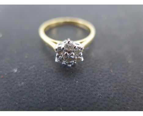 An 18ct yellow gold and diamond ring, the approx. 1/16 ct diamond surrounded by six smaller diamonds - Weight approx. 3.5gms 