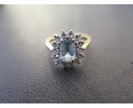 An 18ct yellow gold cluster ring set with a central pale blue Ceylon sapphire surrounded by 14 small diamonds - ring size K -