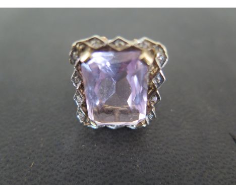 A 14ct yellow gold ring with large rectangular cut light purple stone surrounded by fourteen small diamonds, size U - Weight 