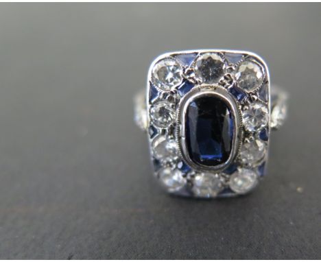 An Art Deco style sapphire and diamond ring, the central sapphire approx. 8 x 4mm, surrounded by ten smaller diamonds and sap