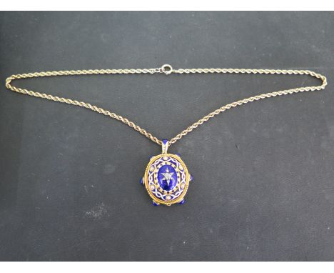 A yellow metal, blue and white enamel seed pearl and diamond memorial pendant with oval glass aperture to back on a 9ct gold 