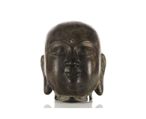 A Chinese patinated bronze head of the Buddha with contemplative downcast eyes and pendulous earlobes.18 cm wide x 21 cm high
