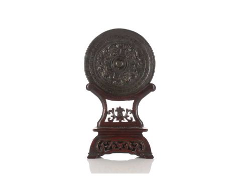 A Chinese bronze mirror, possibly Han dynasty, of circular form, cast with a pierced central boss framed by four character ma