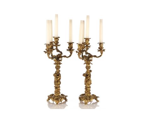 A pair of gilt bronze four sconce figural candelabra of rococo form. Each column is cast with embracing cherubs amongst scrol