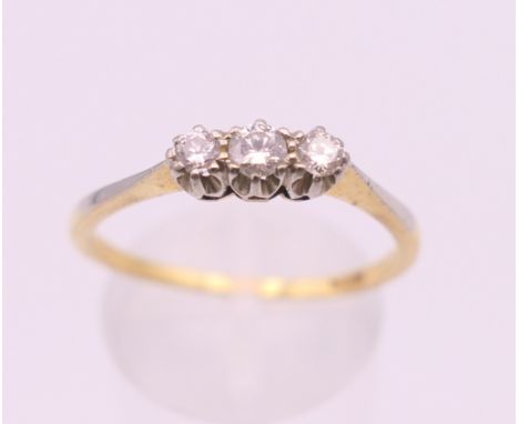 An 18 ct gold three stone diamond ring. Ring size R/S. 2.6 grammes total weight.