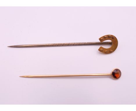 A 15 ct gold horseshoe stick pin and another. Horseshoe pin 5.5 cm long. 1.5 grammes total weight.