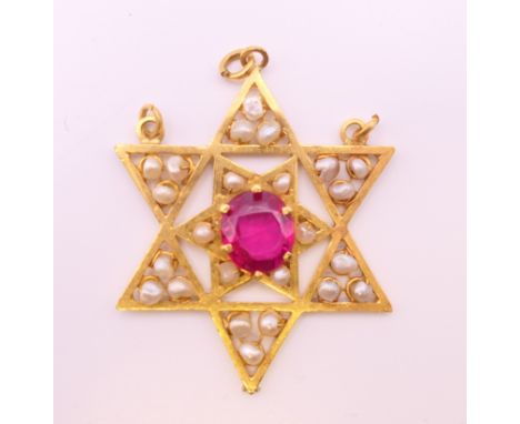 An unmarked gold Burmese ruby and seed pearl star form pendant.  4.5 cm high. 11.4 grammes total weight.