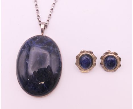 A silver and lapis pendant on chain and a pair of earrings.  Pendant 4 cm high excluding suspension loop, chain 66 cm long, e
