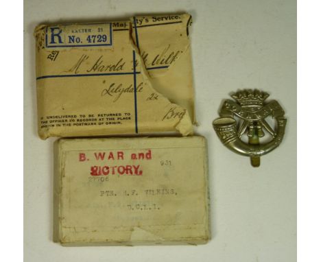 A Cornwall Light Infantry white metal cap badge with slider together with an empty WWI medal postage box and envelope for Pte