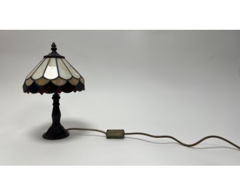 A stained glass Art Nouveau style desk lamp with red and white stained glass shade in a panel design and acorn finial to top,