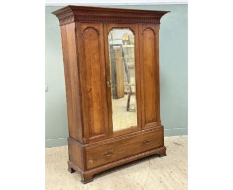 A 19th century mahogany wardrobe, with a moulded cornice above a central bevelled mirror door flanked by a pair of carved pan