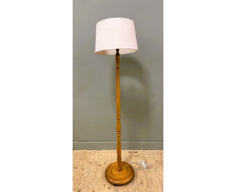 A 20th century oak floor-standing standard lamp, with central carved column on a circular base, with a cream lampshade: h.x 