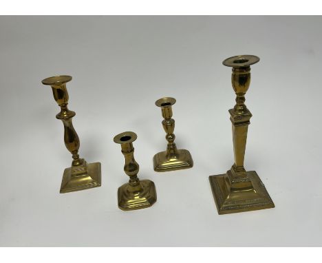 A collection of cast brass candlestick holders comprising, a tall Georgian example of classical form with beaded border and d