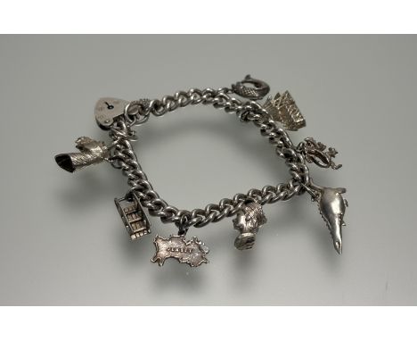 A silver kerb link chain charm bracelet with heart-shaped padlock and safety chain and eight charms to include Nessie, a hors