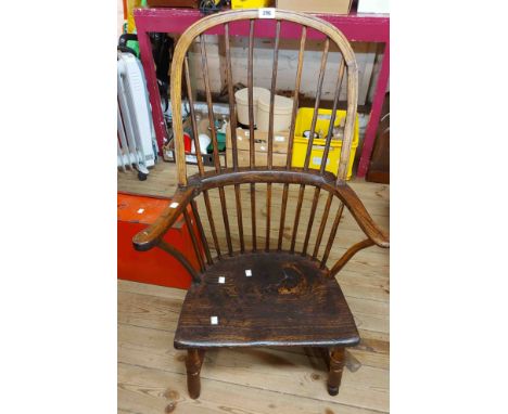 An antique elm Windsor hoop stick back elbow chair with moulded solid seat, set on reduced turned supports