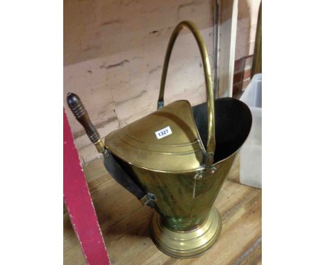 A brass coal scuttle of helmet form with a wooden handled shovel