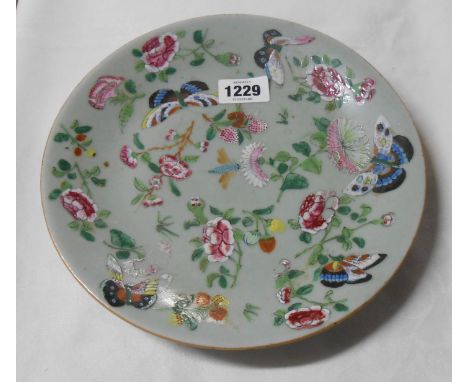 A 19th Century Chinese porcelain plate with famille rose decoration, depicting flowers and butterflies, on a celadon ground -